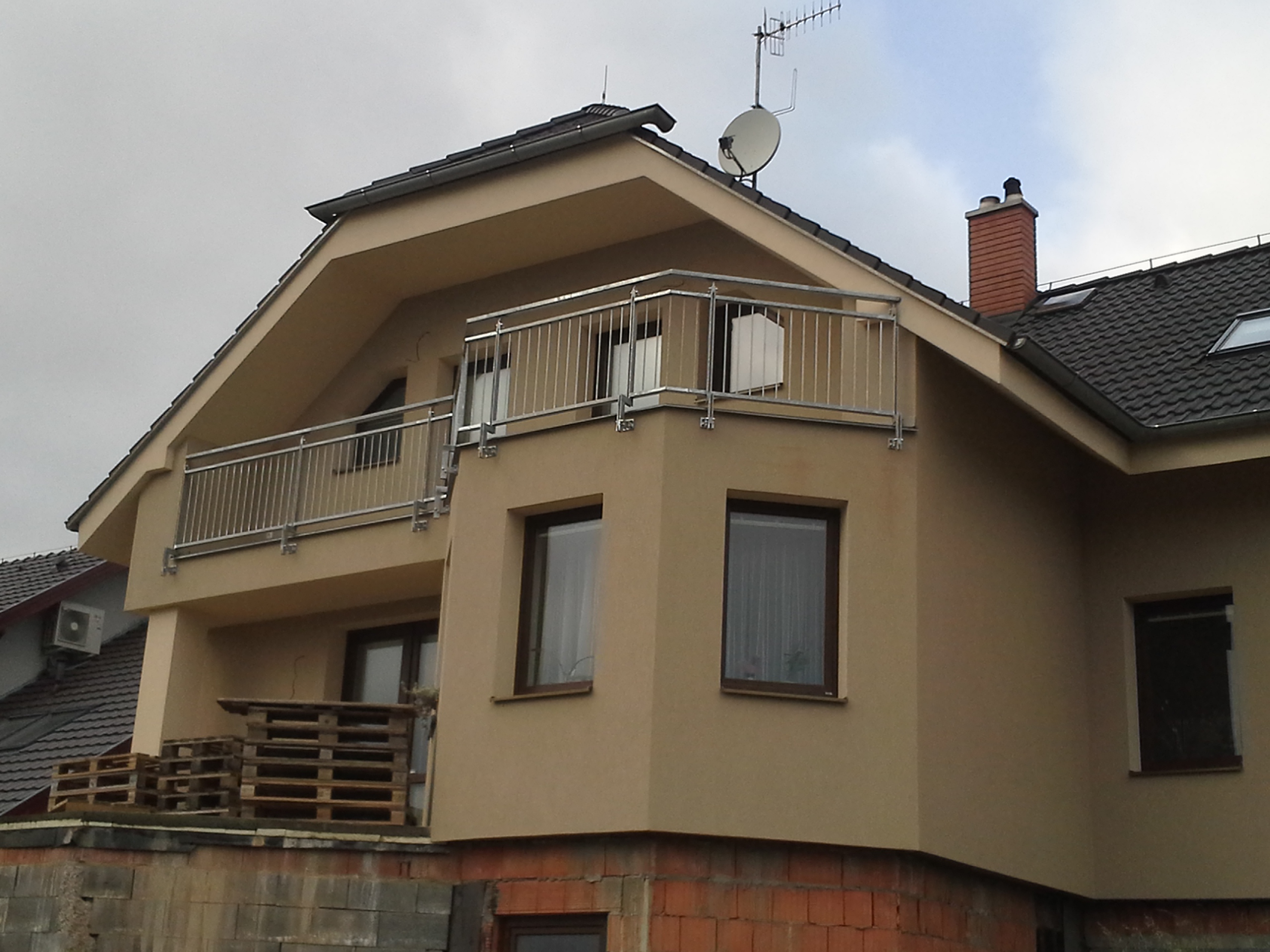 Šikmý pohled zprava na členitý balkón rodinného domu ve Slaném a jeho zinkované zábradlí.