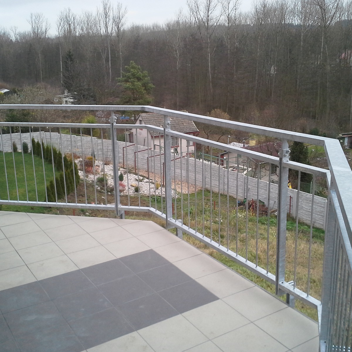 Žárově zinkované zábradlí se svislými tyčemi v rohu členitého balkónu ve Slaném.