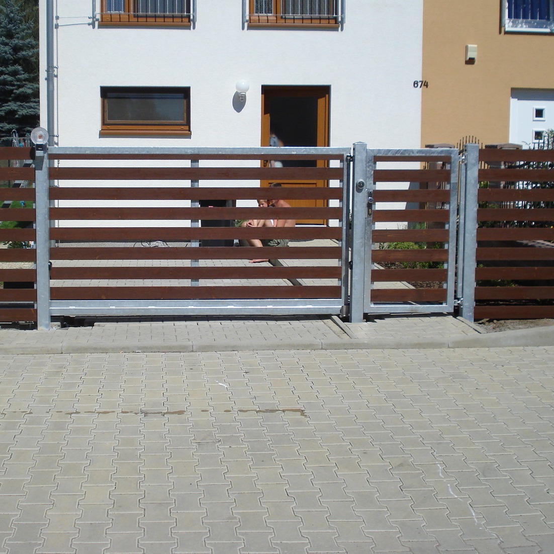 Čelní pohled na samonosnou bránu a vstupní branku s vodorovnou dřevěnou výplní v Nučicích.