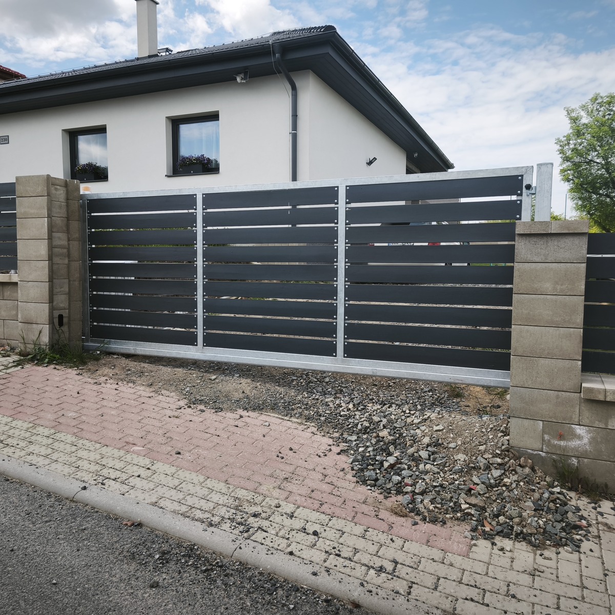 Samonosná brána v Tuřanech po doplnění tmavých vodorovných dřevěných prken zákazníkem.