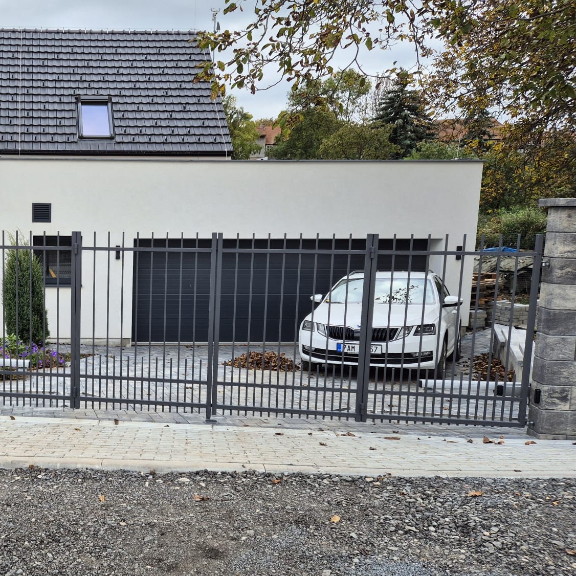 Čelní pohled z ulice na dokončenou antracitovou vjezdovou bránu se svislou tyčovou výplní v Panenském Týnci.
