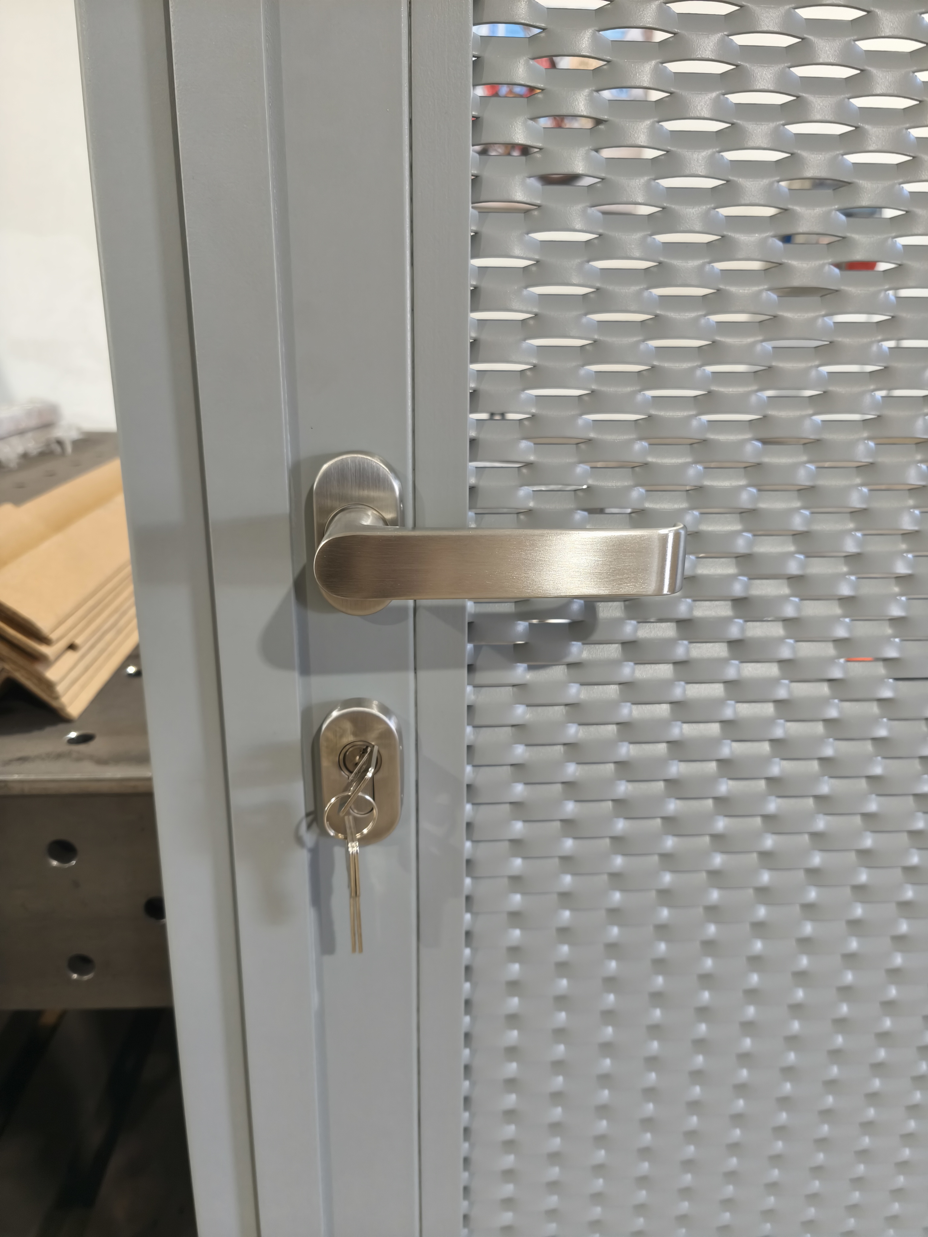 Detail kliky a cylindrické vložky na dokončených dveřích s tahokovem v šedé barvě RAL 7042.