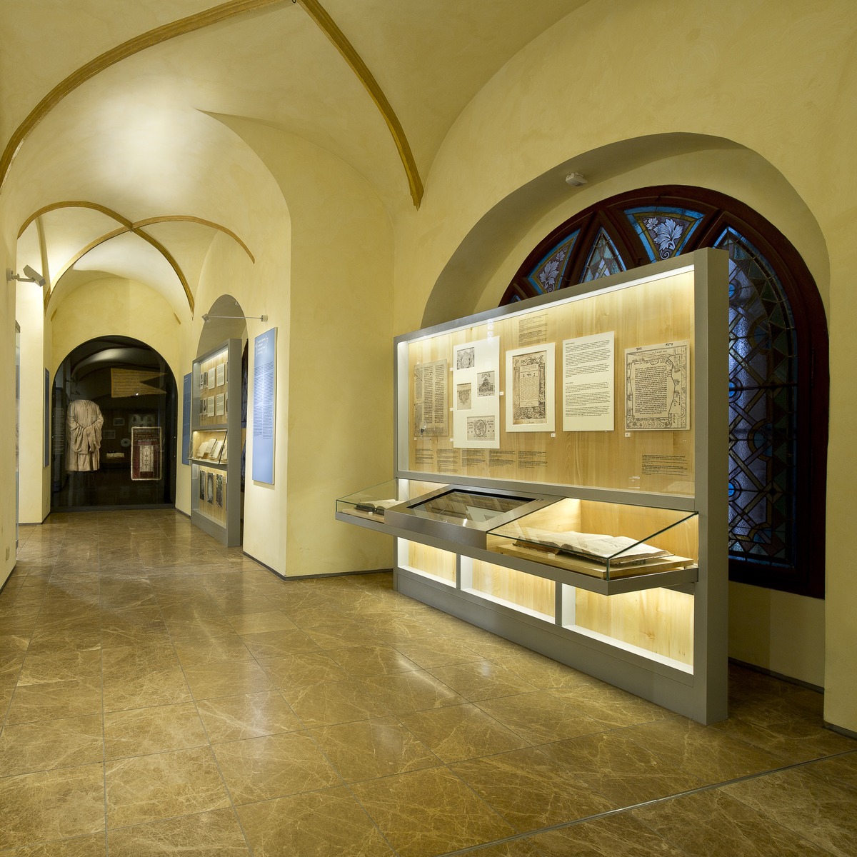 Dokončená osvětlená výstavní vitrína s kovovou konstrukcí v interiéru Maiselovy synagogy v Praze.