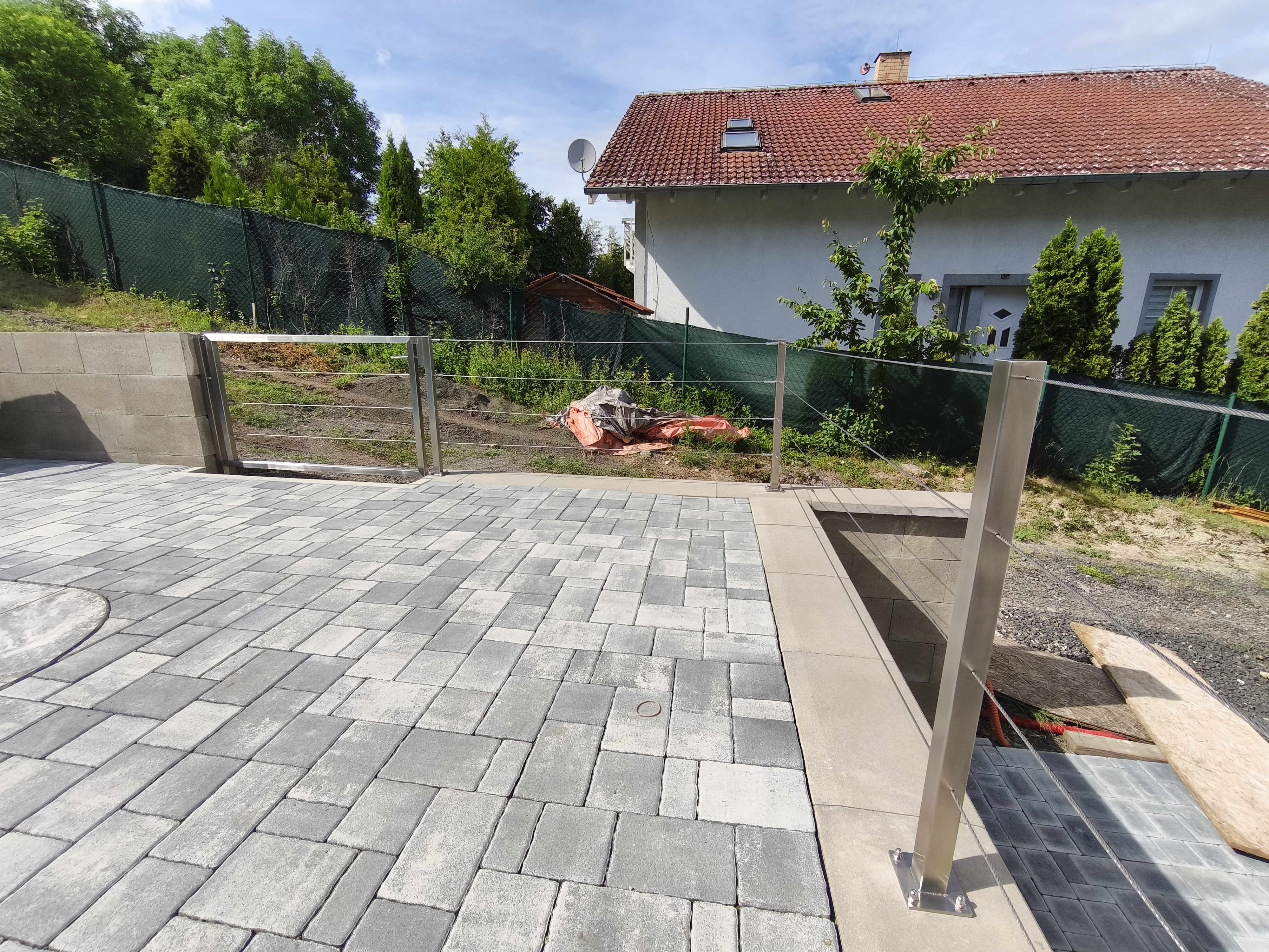 Pohled na rohové uspořádání lankového zábradlí, kotvené sloupky a branku u bazénové plochy v Rané.