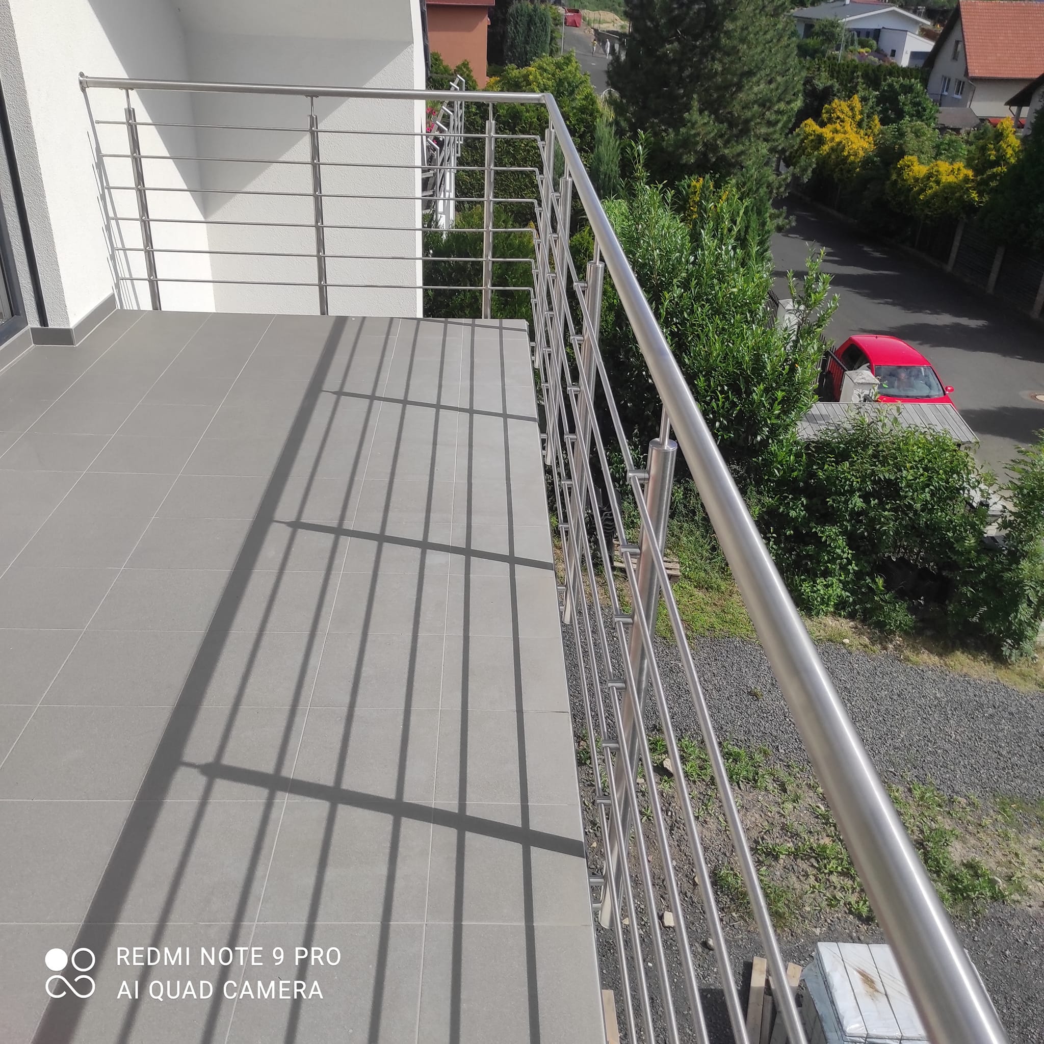 Pohled podél nerezového madla a vodorovné výplně zevnitř balkónu v Rané.