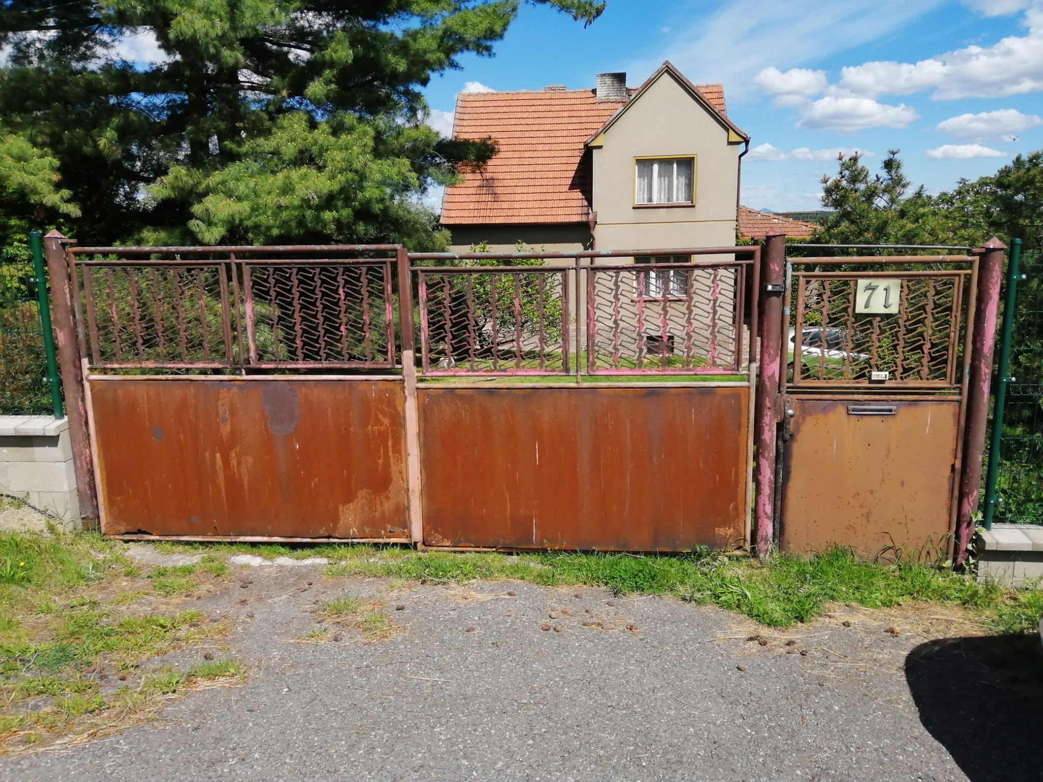 Původní dvoukřídlá kovová vrata s plechovou spodní částí a branka se stopami koroze v Hvězdě před výměnou v roce 2017.