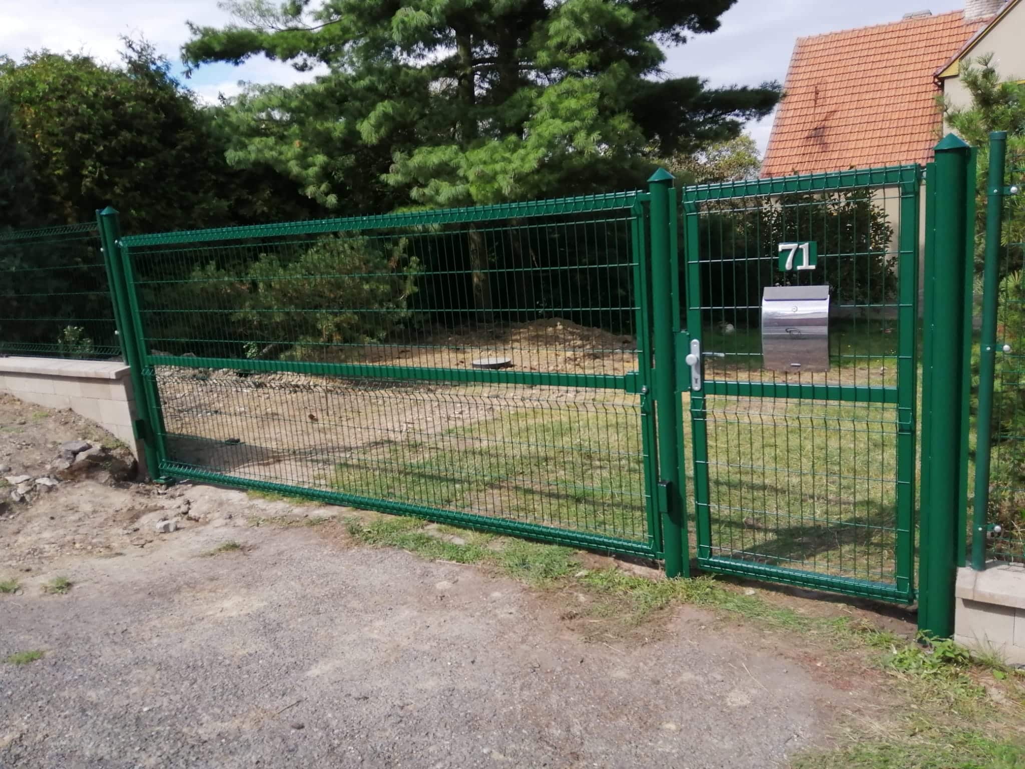Dokončená zelená vjezdová brána s brankou a navazujícími plotovými dílci s 3D pletivem v Hvězdě, pohled z boku.