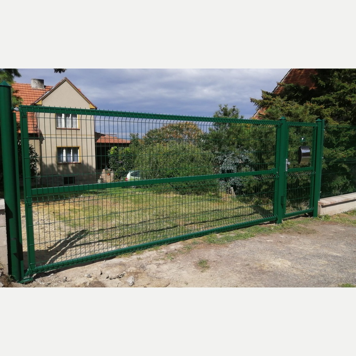 Zelená jednokřídlá vjezdová brána a samostatná branka s 3D pletivem v Hvězdě po realizaci v roce 2017.
