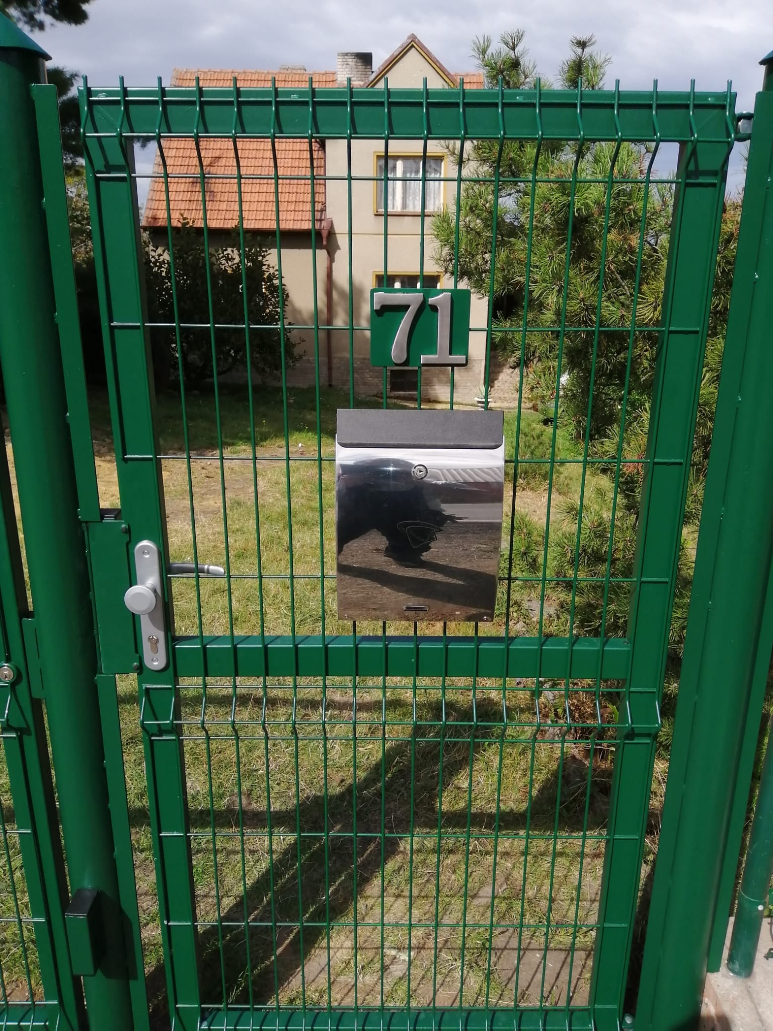 Čelní pohled na zelenou vstupní branku s 3D pletivem, kováním a poštovní schránkou v Hvězdě po realizaci v roce 2017.