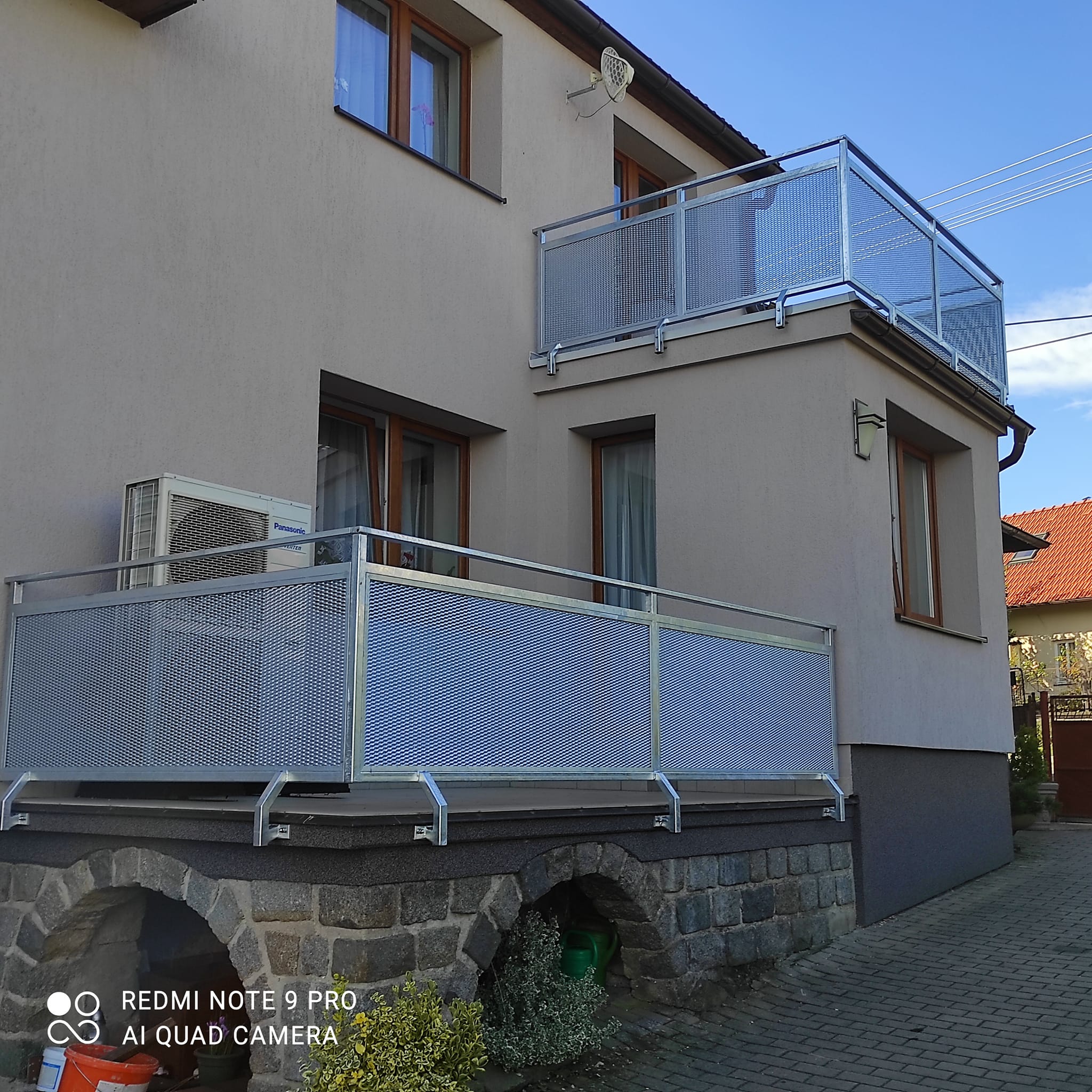 Rodinný dům v Černých Voděradech se dvěma dokončenými zinkovanými zábradlími s tahokovem na terase a horním balkónu.